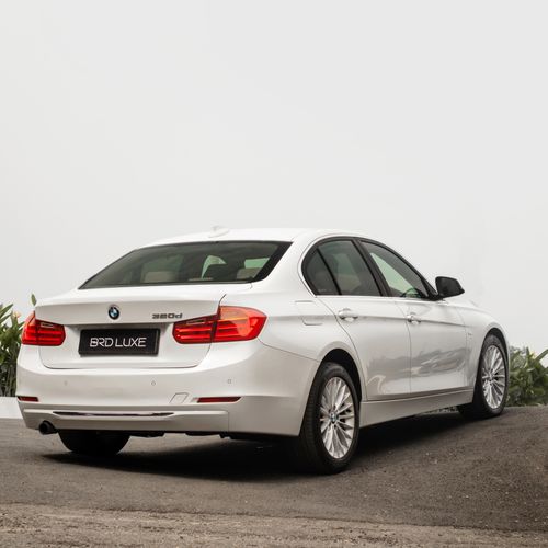Free Sleek white BMW 320d parked on a concrete road, showcasing luxury design features. Stock Photo