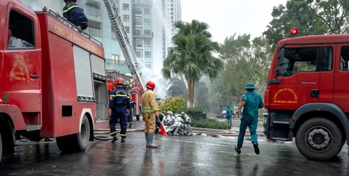 Free Firefighters and trucks at a residential fire scene, managing an emergency operation. Stock Photo