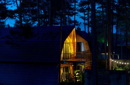Free A cozy wooden cabin nestled in a forest, warmly illuminated at night, creating a serene ambiance. Stock Photo