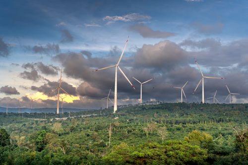 Free A picturesque view of wind turbines across a lush, green landscape under a cloudy sky, showcasing sustainable energy. Stock Photo