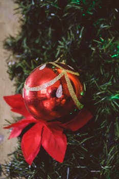 Close-up of a red Christmas ornament with festive decor on a tree.