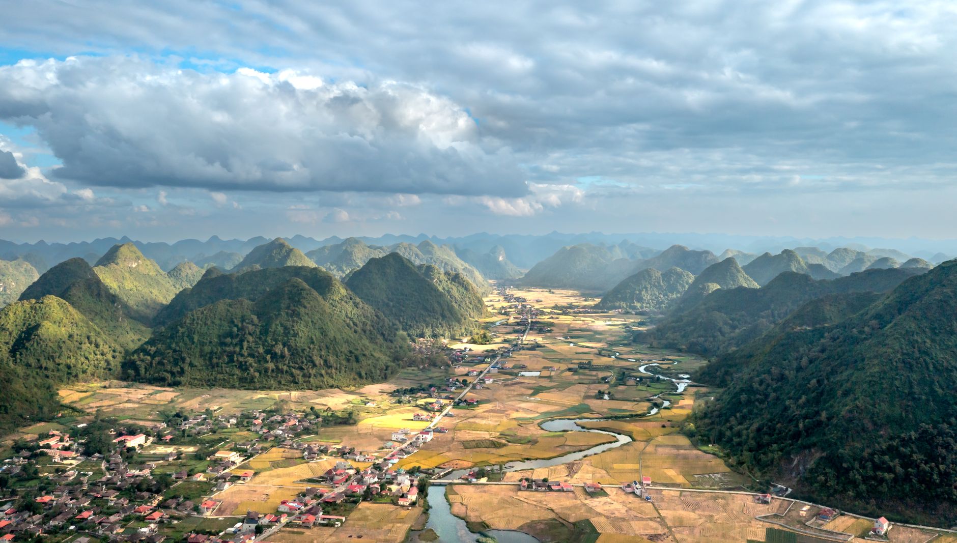 Stunning aerial shot of Bac Son Valley's lush landscape with mountains and a river.