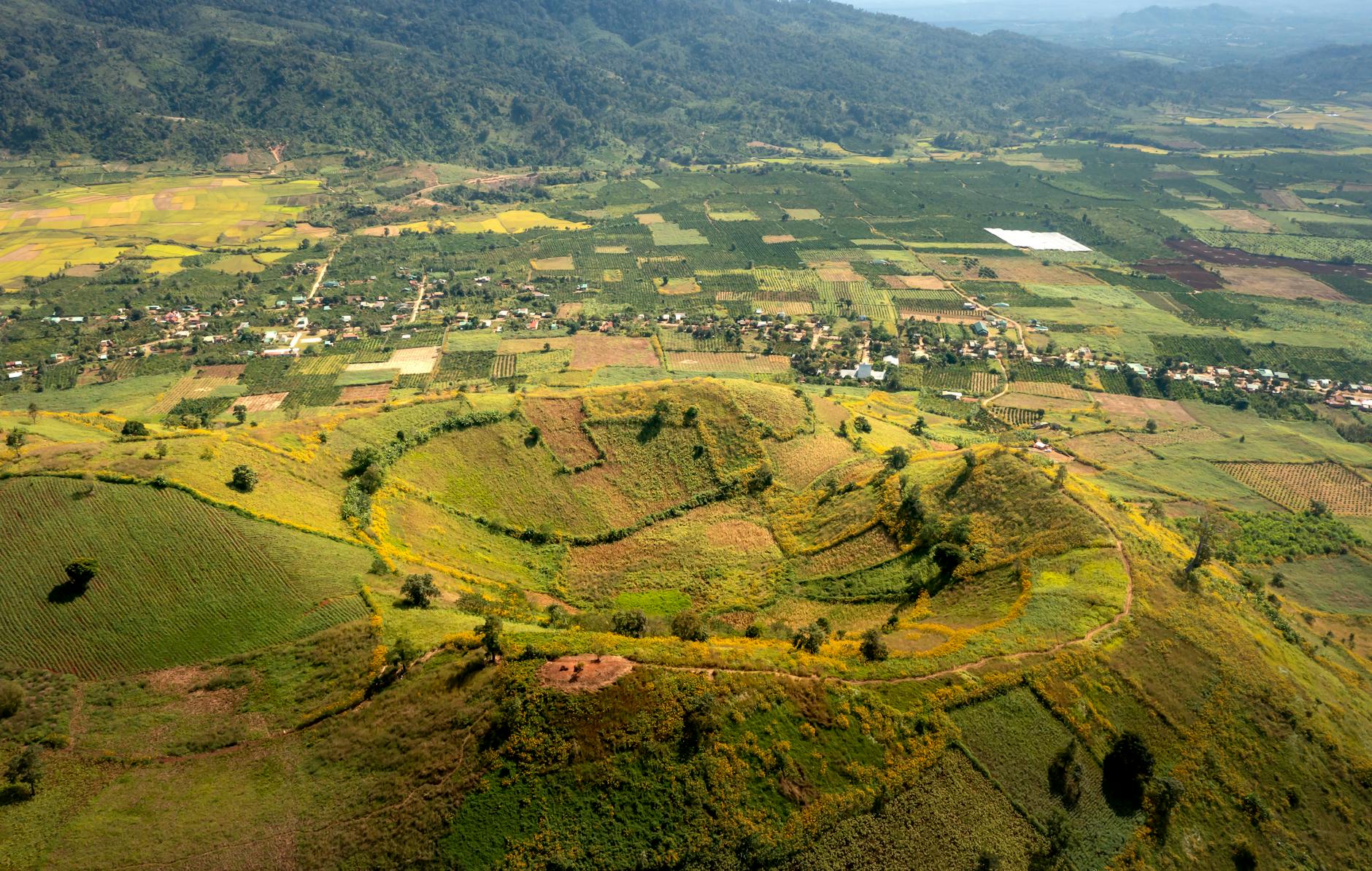 Explore the stunning aerial view of lush fields and a volcano in Vietnam.