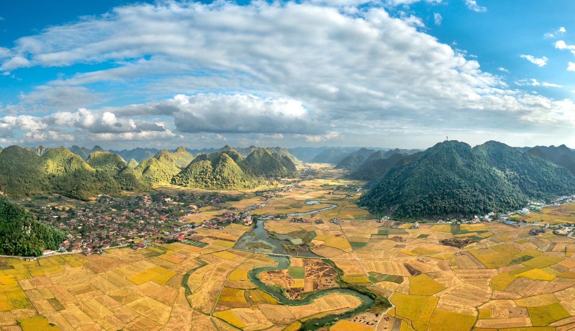 A breathtaking aerial panorama of Bac Son Valley with lush mountains and golden fields.
