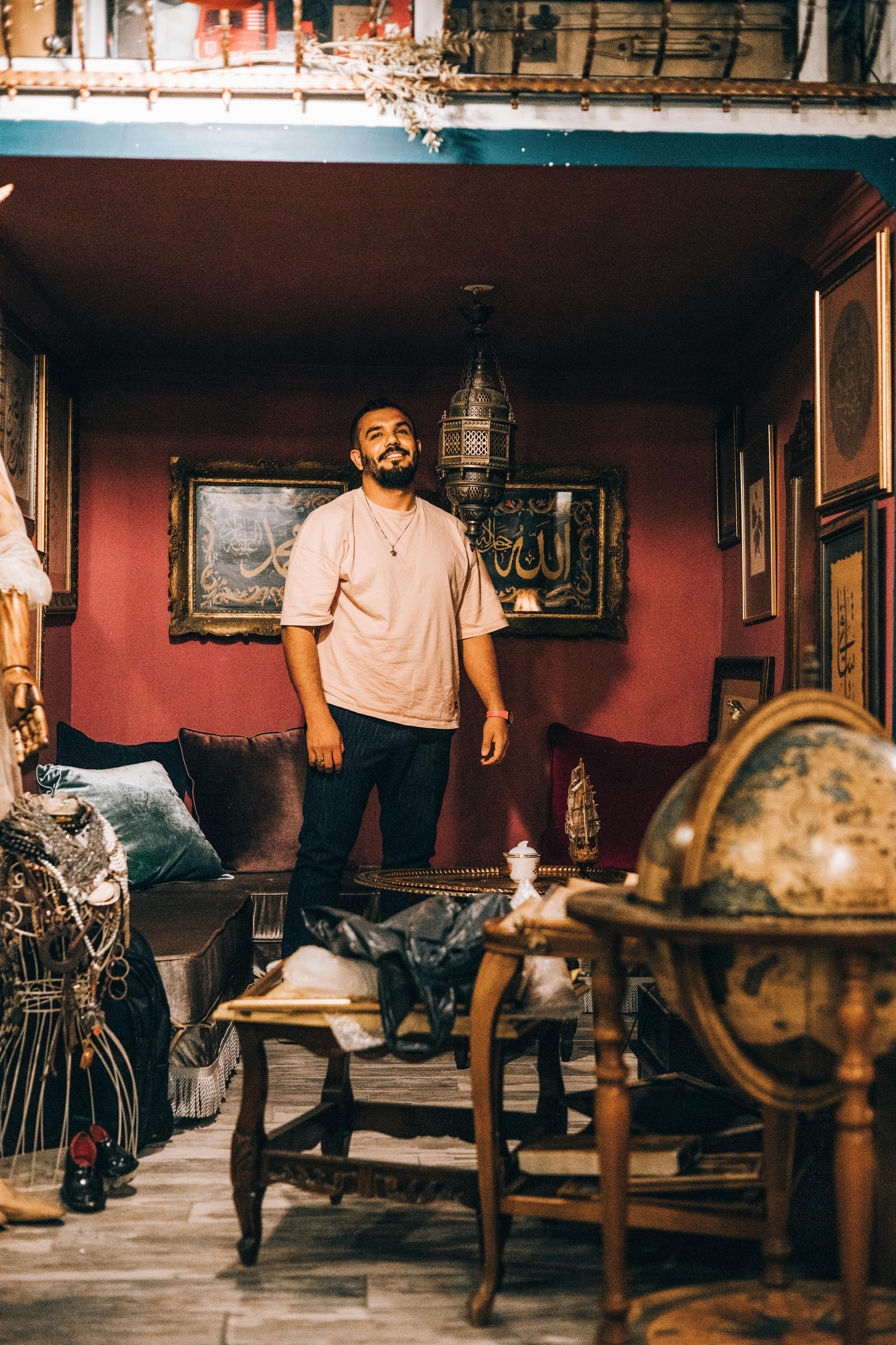 Smiling man in a Turkish museum with Ottoman decor, intricate artifacts, and warm lighting.