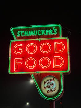 Vibrant neon sign displaying 'Good Food' at night outside Schmucker's Diner, Toledo, Ohio.