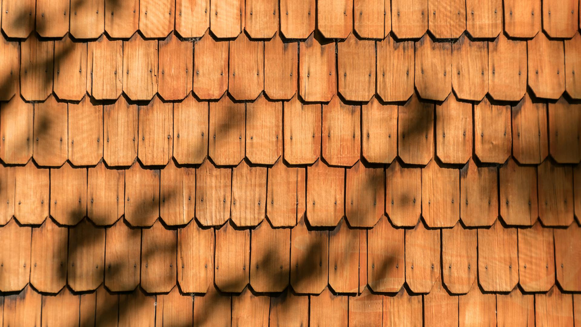 Close-up view of sunlit wooden shingles on a wall, casting shadows in Frutillar Bajo, Chile.