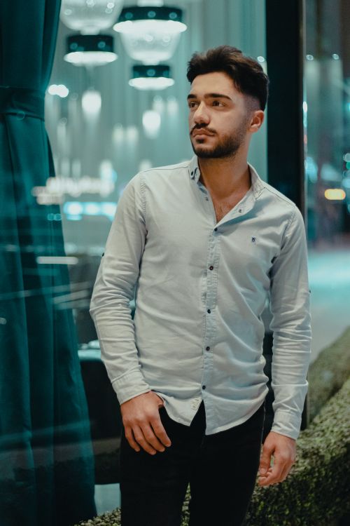 Free Young man in a casual shirt stands confidently indoors, captured in a vertical shot. Stock Photo