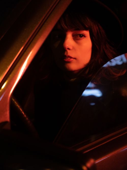 Free A woman sits in a car at night, illuminated by dramatic red lighting. Stock Photo