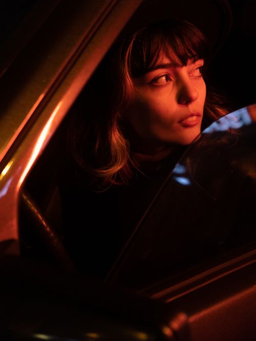Free Woman gazing out car window at night, illuminated by moody lighting. Stock Photo