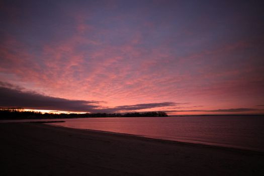 Capture of a serene ocean scene with a dramatic pink sky at dawn, showcasing nature's beauty.