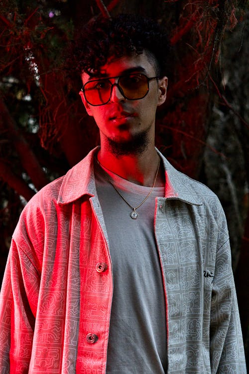 Young Man in a Shirt and Sunglasses Standing in Red Lighting 