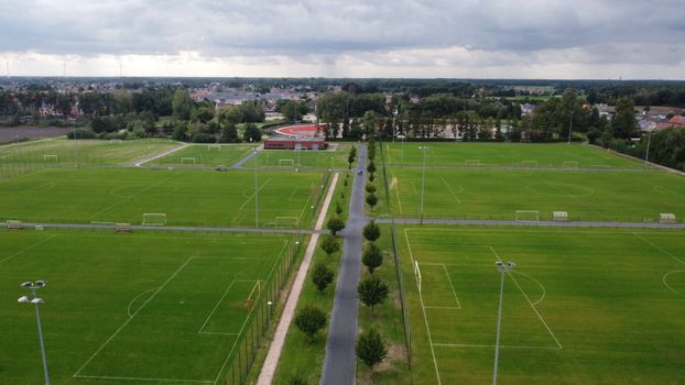 Drone shot of soccer fields and stadium in Arendonk, Flanders, Belgium under cloudy sky.