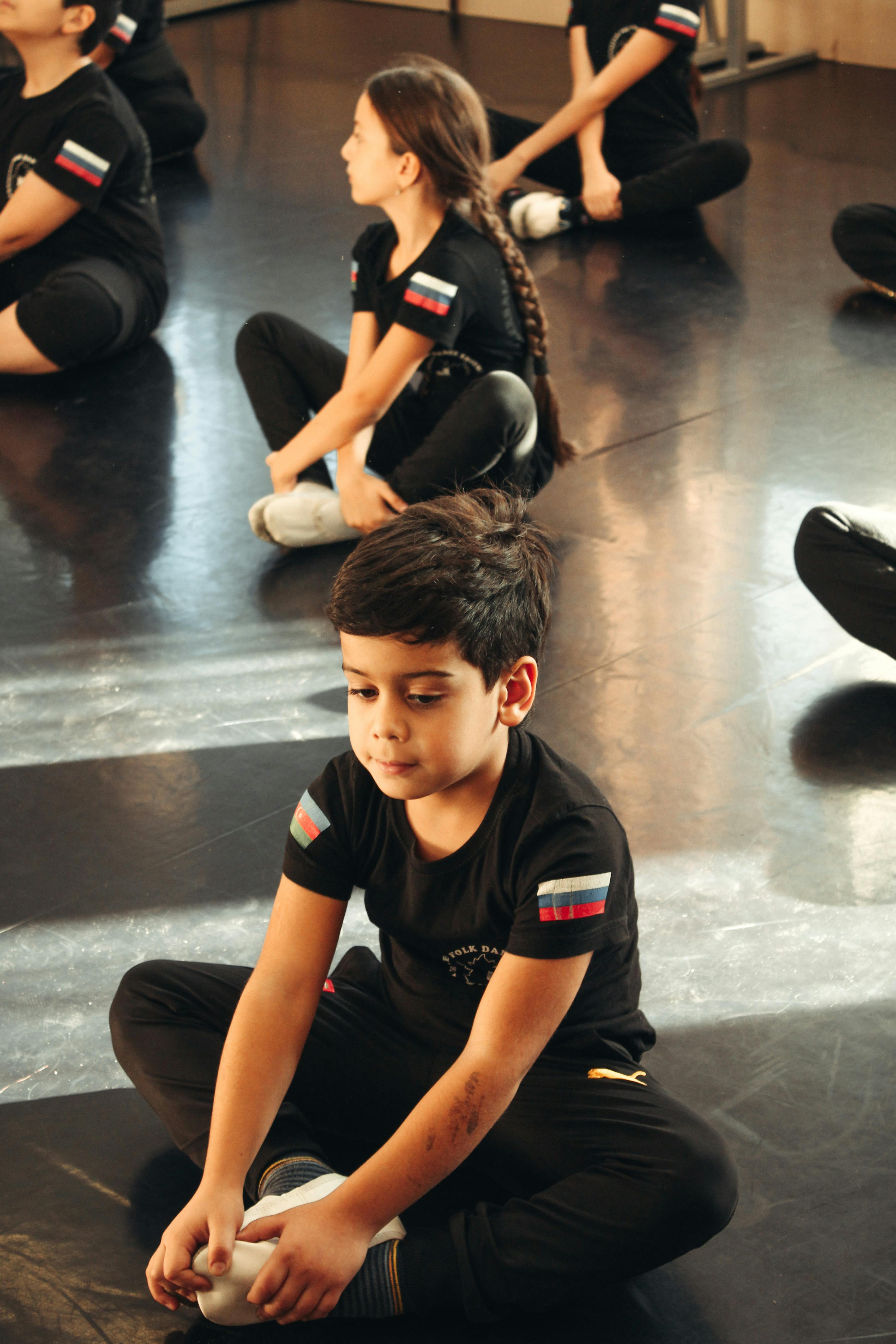 Group of children sitting on gym floor practicing yoga in a relaxed setting.