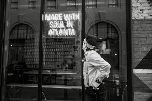 A Grayscale of a Man Looking at a Neon Signage