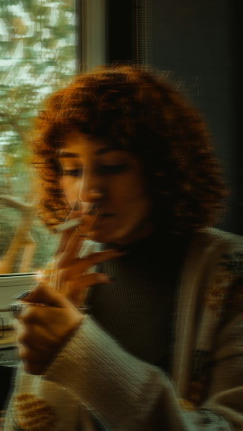 Photo of a Woman with Curly Hair Smoking a Cigarette