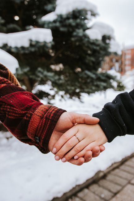 Closeup of a couple holding hands outdoors in winter, showcasing love and romance.