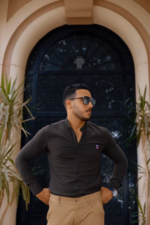 Free Stylish man in sunglasses poses confidently outdoors. Chic and modern fashion photography. Stock Photo
