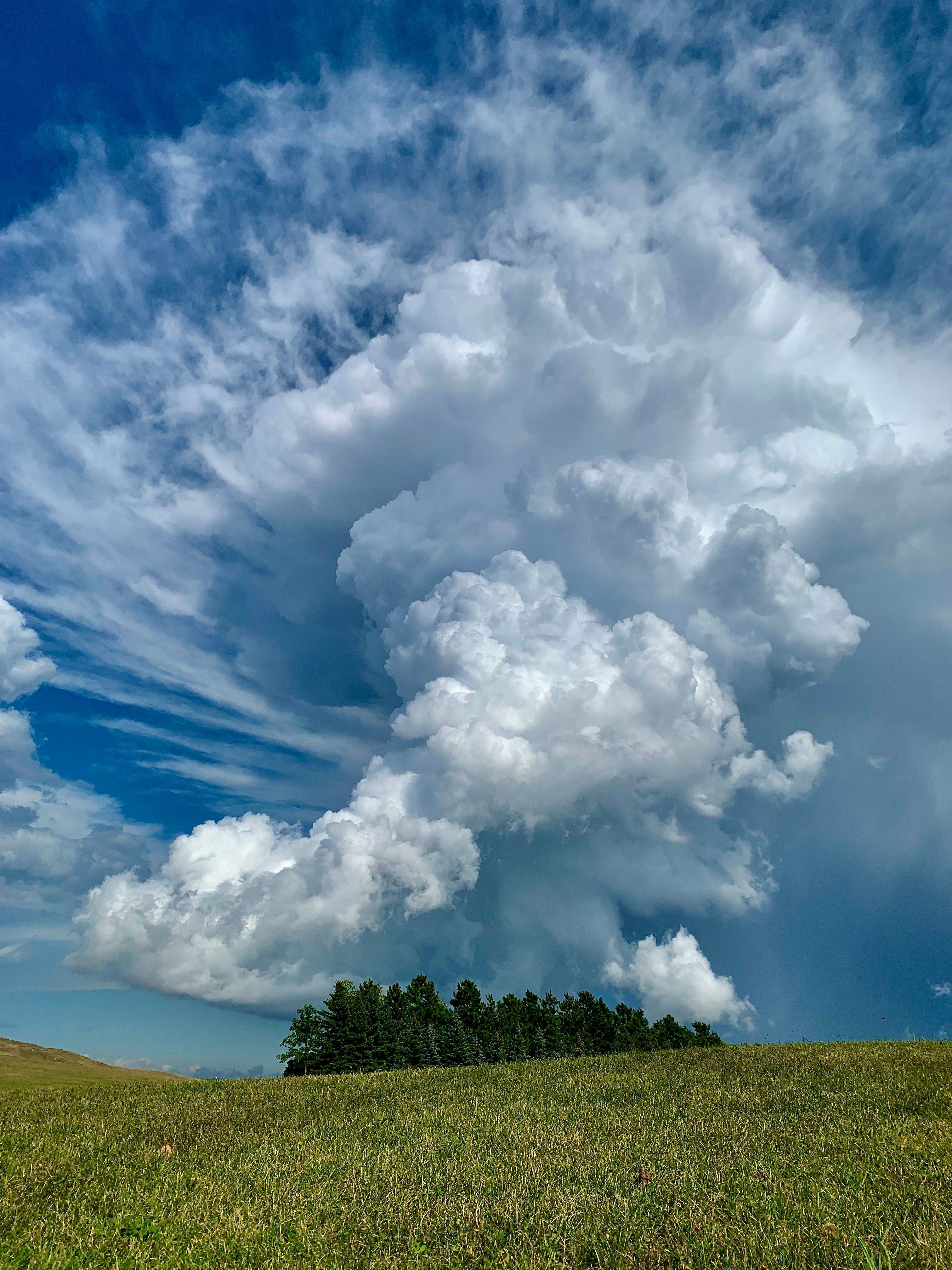 Dramatic cumulus clouds tower over a tranquil North Dakota landscape.