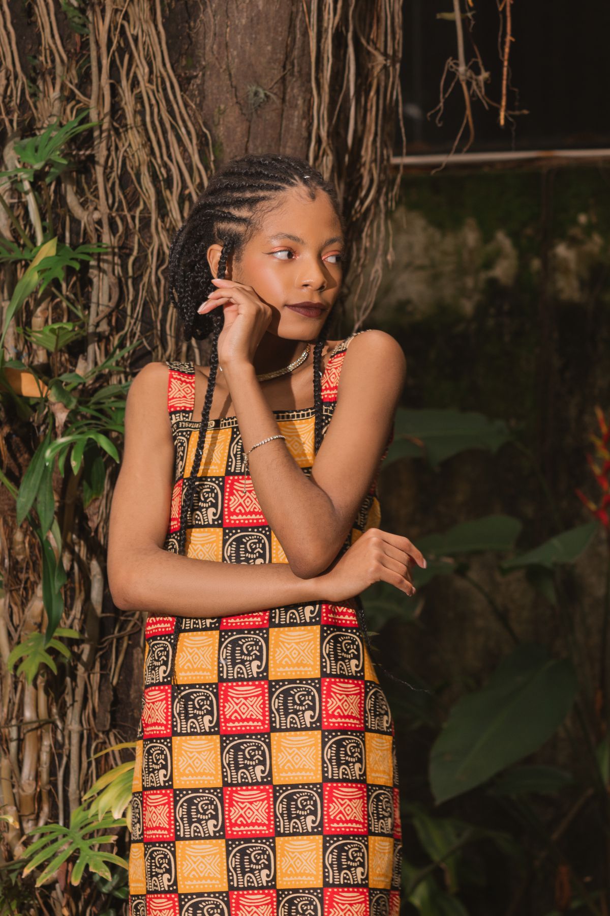 Woman in a checked Kitenge tunic in a leafy garden