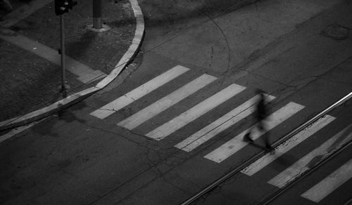 Free Blurred silhouette crossing a city street at night. High angle view captures urban life. Stock Photo