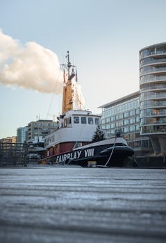 A vintage tugboat docked in the bustling Hamburg harbor, with modern architecture in the background.