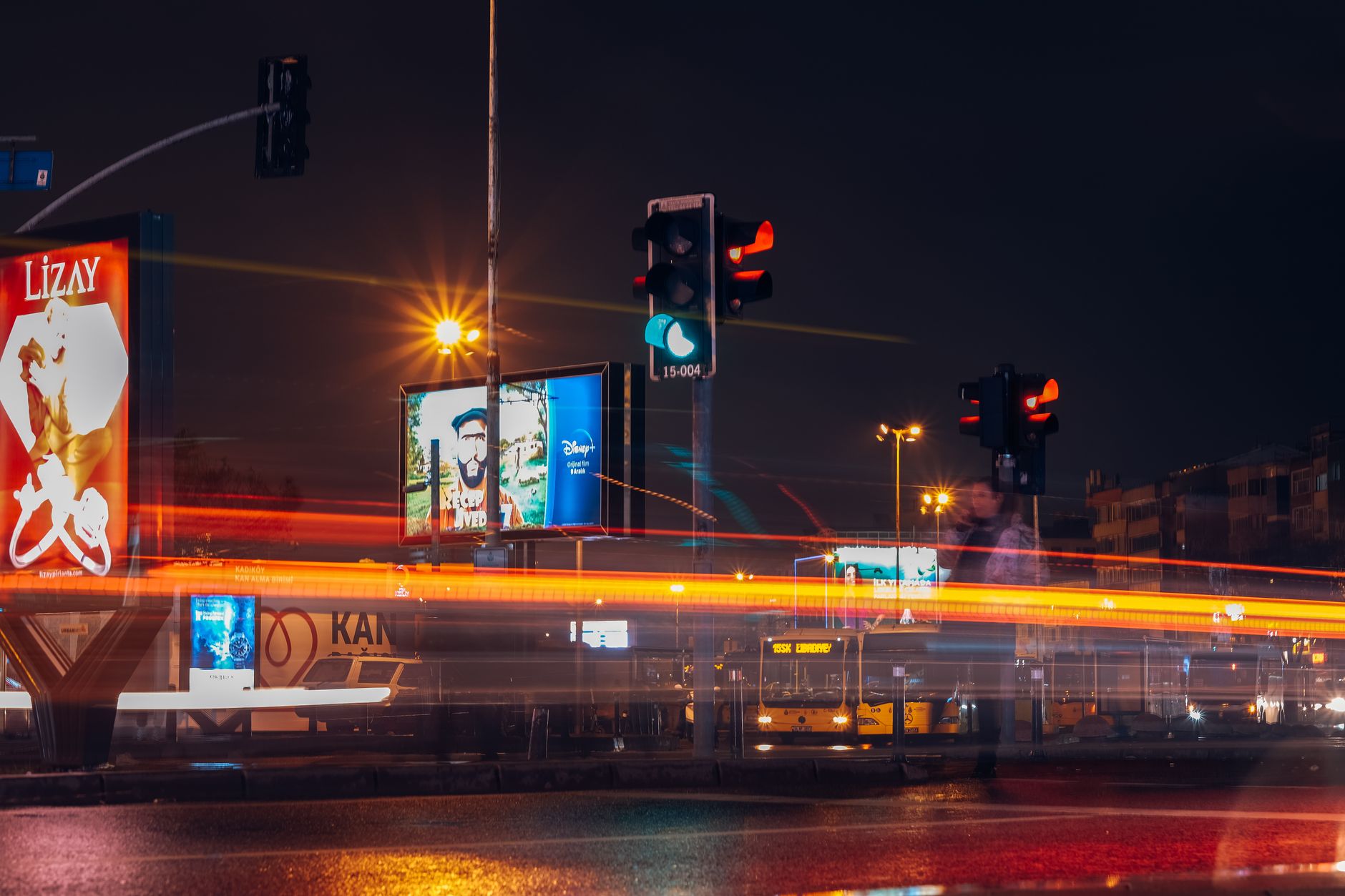 A vibrant city street scene captured at night with long exposure showing traffic lights and light trails.