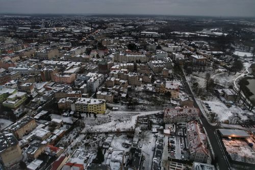 Free Aerial view of a snow-covered cityscape, showcasing buildings and roads under winter skies. Stock Photo