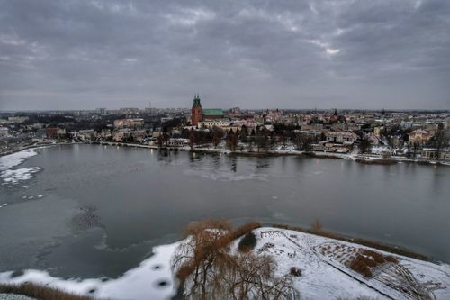 Free Aerial view of a cityscape with a frozen river and snow-covered landscape during winter. Stock Photo