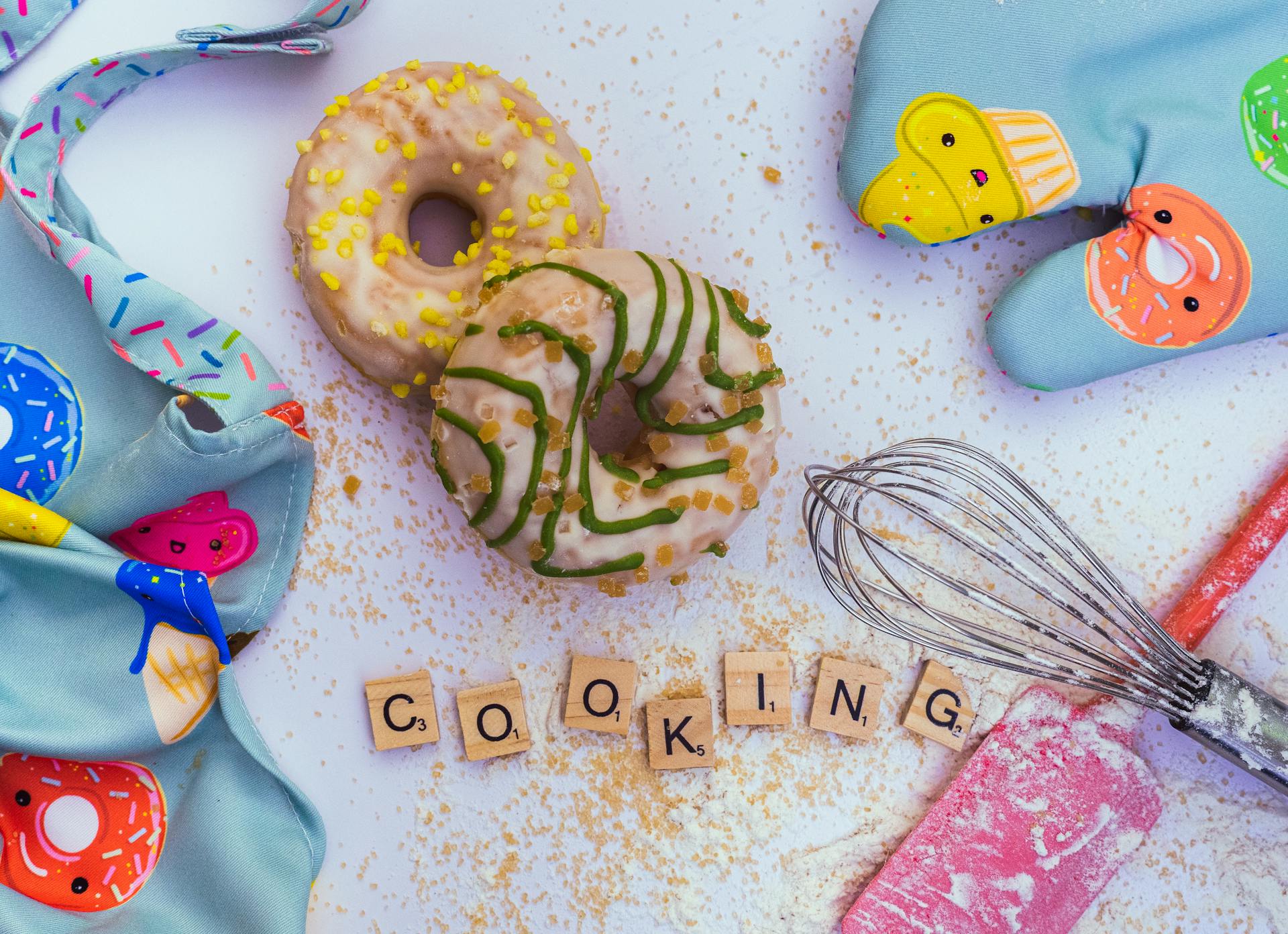 Donuts Lying on Table Next to Baking Utensils and Colorful Apron