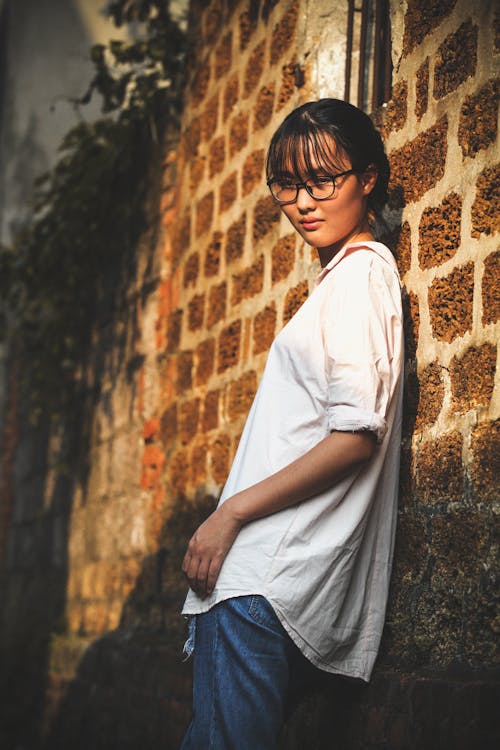 Free Woman Leaning on Brown Brick Wall Stock Photo