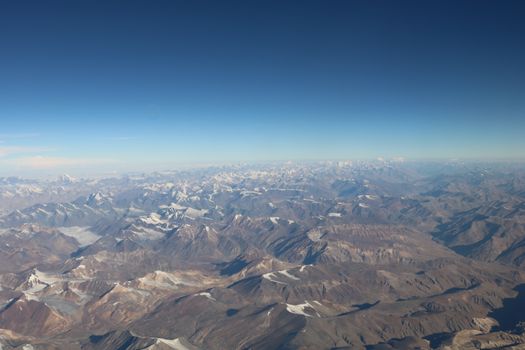 Breathtaking aerial view of the Himalayan mountain range from above, showcasing snow-capped peaks under clear skies.