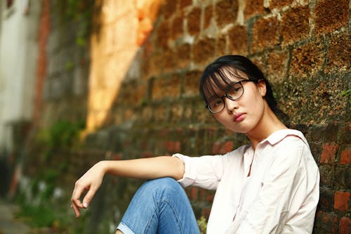 Free Woman Sitting Against Wall Stock Photo
