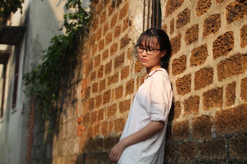 Woman Leaning on Brown Brick Wall