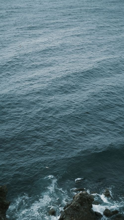Free A serene view of ocean waves gently crashing against a rocky shore, showcasing a tranquil seascape. Stock Photo