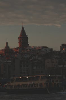 Dramatic view of the Galata Tower with a ferry boat at twilight, capturing the essence of Istanbul's skyline.
