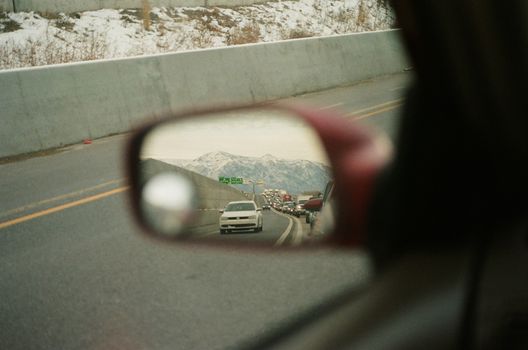在一辆车的侧视镜中反射出的道路和山脉，显示了交通情况。 - 相关推荐