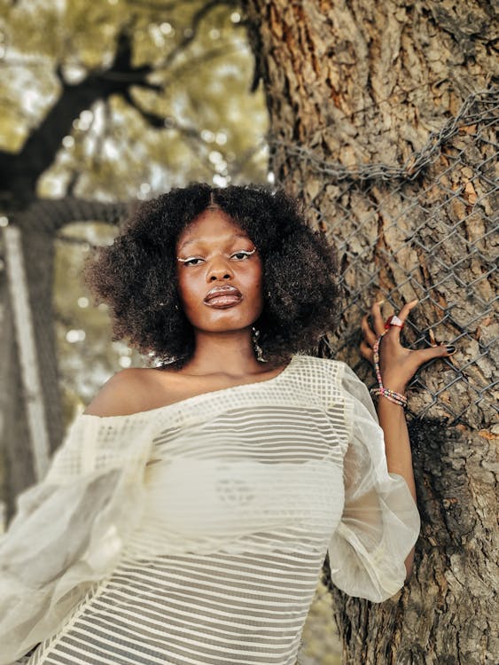 Young Woman in a White Dress Posing by a Tree