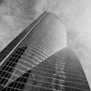 黑白照片中，一座高耸入云的当代玻璃摩天大楼凸显了城市建筑