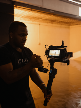 A focused camera operator using a stabilizer in an indoor studio setting.