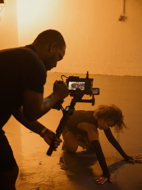 Man Filming a Female Fashion Model Posing in an Empty Room