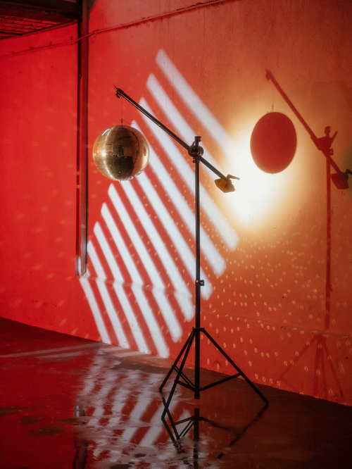 Free Hanging disco ball on tripod creating light play and shadows on a red wall. Stock Photo