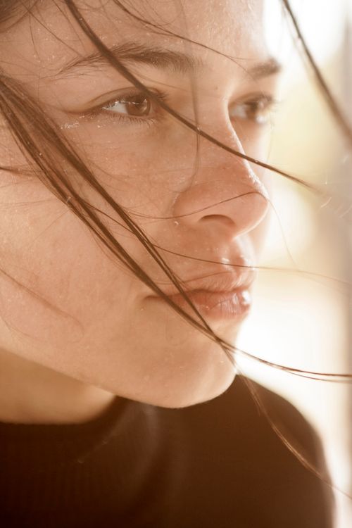 Free Close-up of a woman's face with hair blowing, conveying contemplation and emotion. Stock Photo