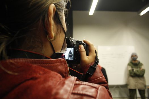 A female photographer taking a picture in a studio environment with a Canon camera.