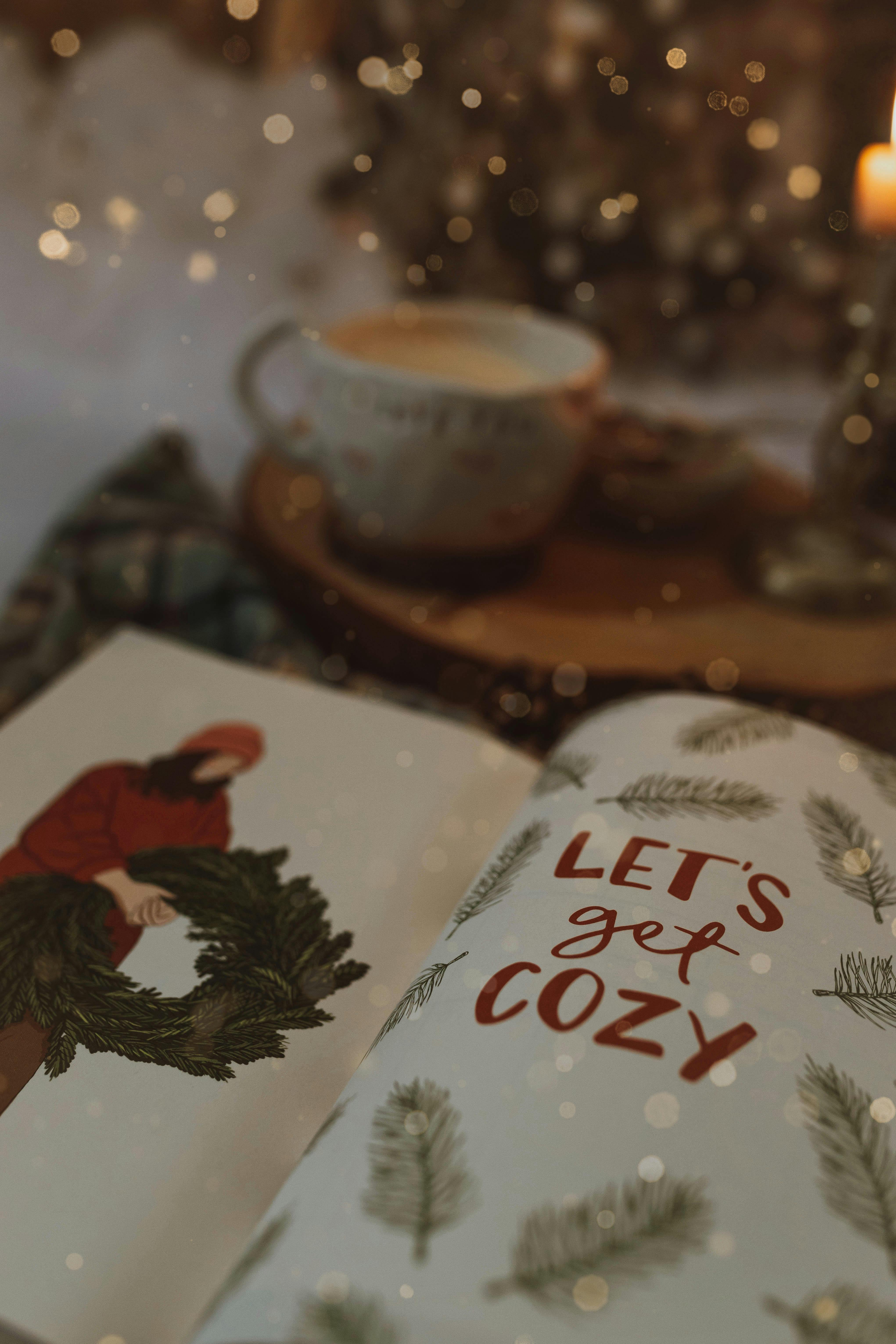 Warm winter scene with a cozy book, candle, and cup creating a homely atmosphere.