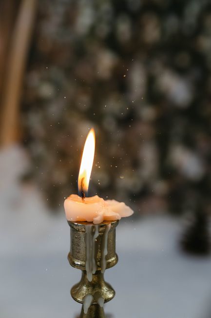 Close-up of a burning candle in a candlestick creating a cozy winter atmosphere.
