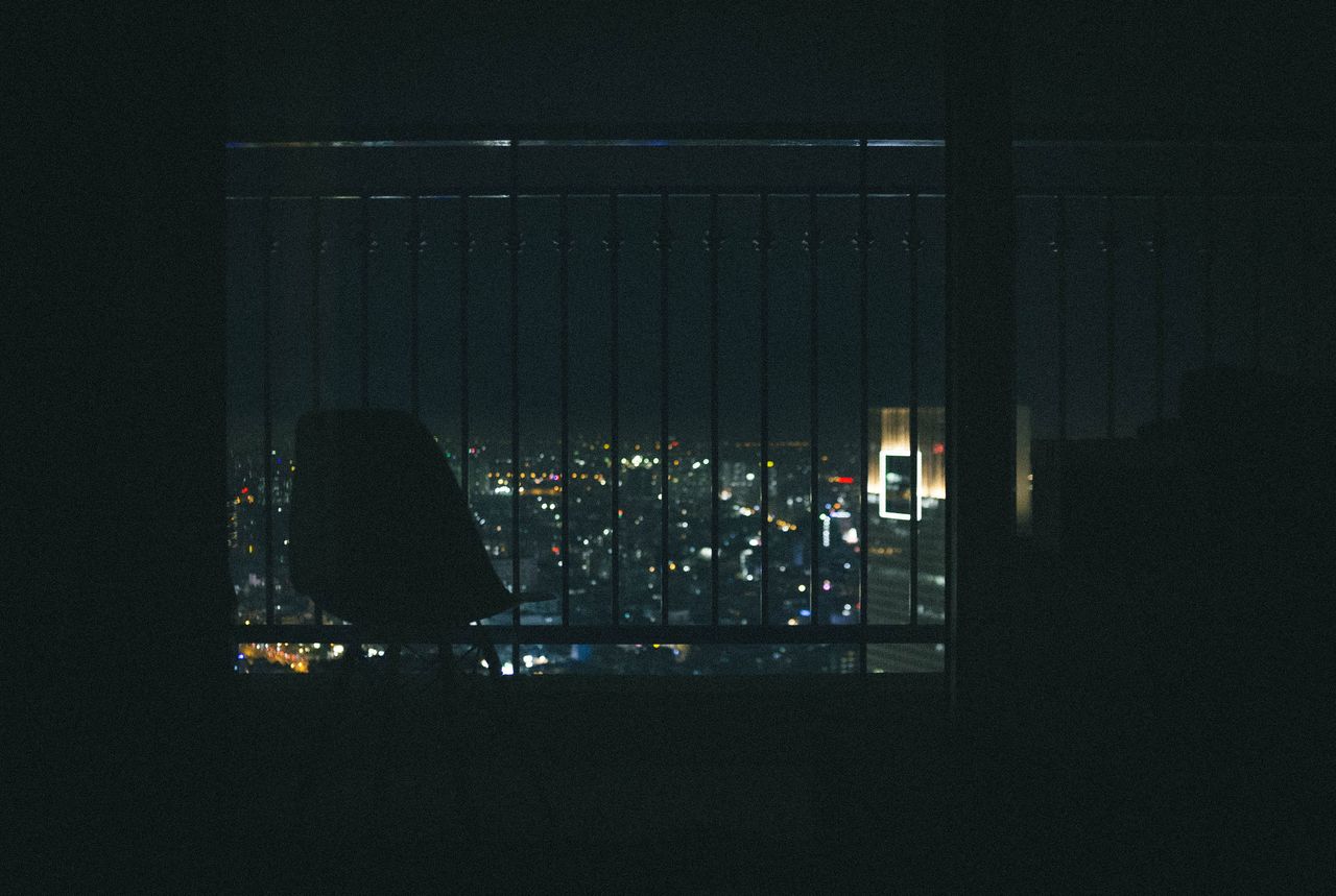 silhouette of a chair on a balcony overlooking the city lights of ho c