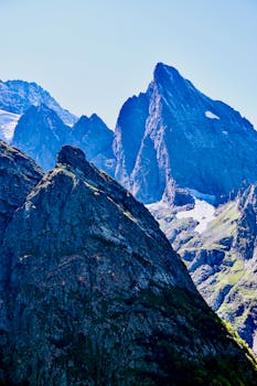 Snow-capped mountain peaks rising under a vibrant blue sky, showcasing stunning natural beauty.