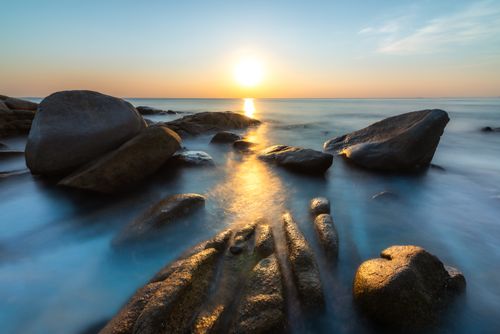 Free Beautiful sunset over smooth rocks by the sea, capturing serene oceanic tranquility. Stock Photo