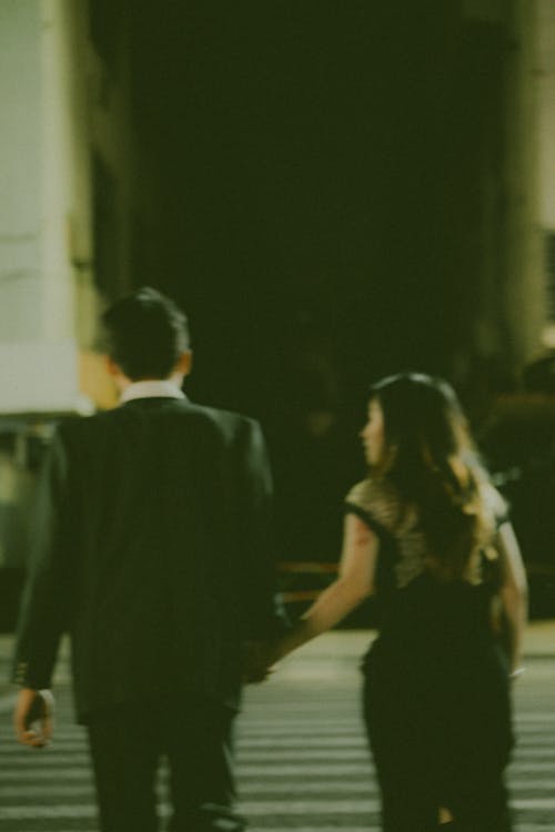 A Blurred Photo of a Man and Woman Crossing a Street
